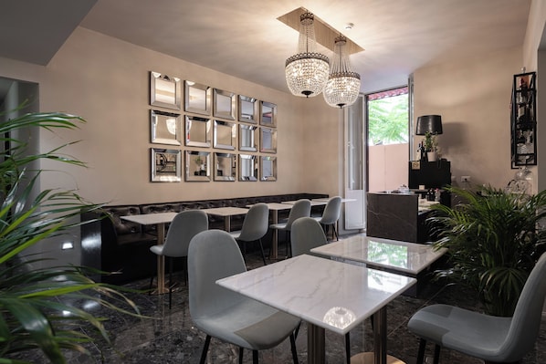 A modern restaurant with marble tables and grey chairs, a wall of mirrors, and a chandelier. - Roma Suite Hotel (Rome)