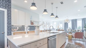 A modern kitchen with a central island, stainless steel appliances, pendant lighting, and a view to the living area. - Nashville Retreat With Hot Tub Private Garage (Nashville)