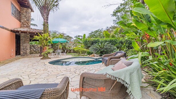 A pool area with wicker furniture and a stone patio.