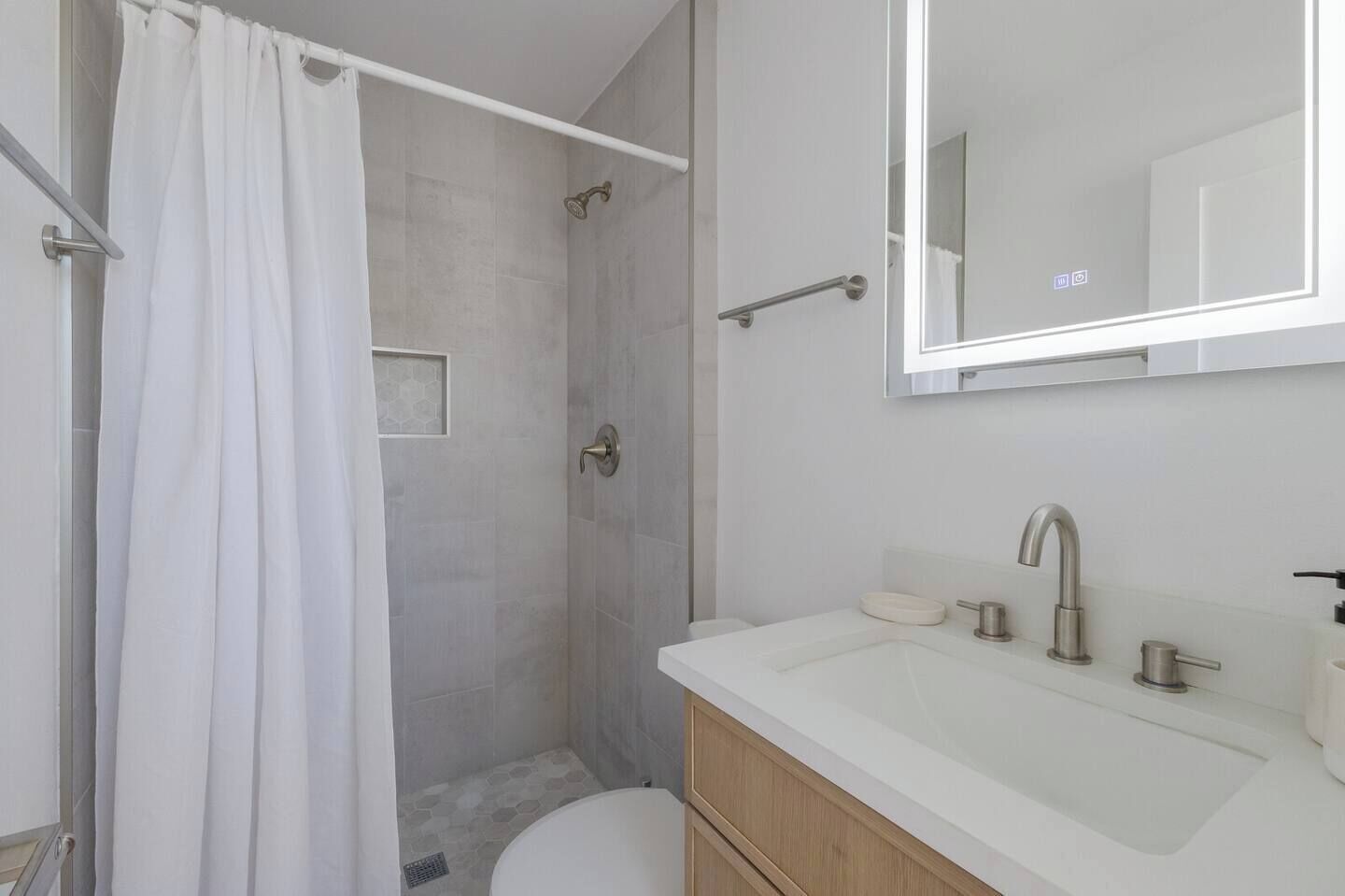 Une salle de bain moderne équipée d’une douche, de toilettes et d’un lavabo.
