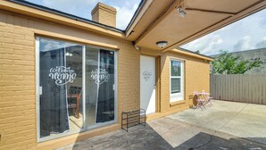 Ein Bungalow mit großer Schiebetür aus Glas und einer kleinen Terrasse mit Gartenmöbeln.
