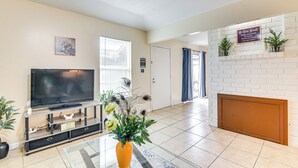 Ein Wohnzimmer mit Flachbildfernseher, einer Zierdevas und einem Kamin aus Backsteinen.