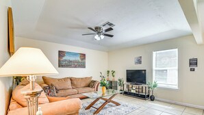 Ein Wohnzimmer mit Sofa, Couchtisch, Lampe, Fernseher und Deckenventilator.