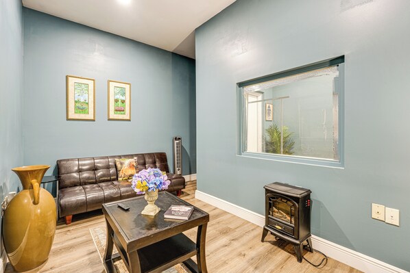 Una sala de estar con un sofá, una mesa de centro con un florero, una chimenea y dos cuadros en la pared.