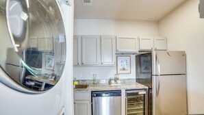 A compact kitchen with white cabinets, a stainless steel dishwasher, a built-in oven, and a refrigerator. - Walk to Restaurants & Bars: Modern Dallas Retreat (Dallas)