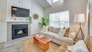 A modern living room with a fireplace, a large flat-screen TV, a sofa, a coffee table, and a floor lamp. - Walk to Restaurants & Bars: Modern Dallas Retreat (Dallas)