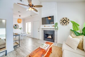 A modern living room with a fireplace, a ceiling fan, and a TV mounted on the wall. - Walk to Restaurants & Bars: Modern Dallas Retreat (Dallas)