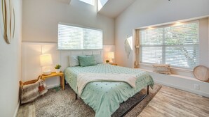 A bedroom with a bed, two bedside tables, a window with blinds, a skylight, and a wall-mounted lamp. - Walk to Restaurants & Bars: Modern Dallas Retreat (Dallas)