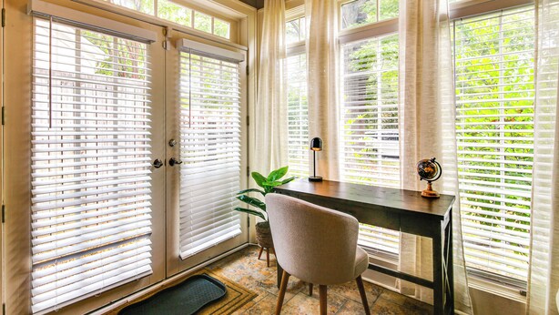 A room with a desk, chair, and a globe on the desk. There are two windows with blinds, and a plant is visible near the windows. - Fire Pit & Yard! Charming Home, 5 Mi to Fedexforum (Memphis)