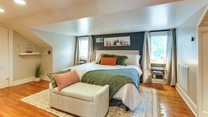A bedroom with a bed, a nightstand, a chair, a window, and a radiator. - Fire Pit & Yard! Charming Home, 5 Mi to Fedexforum (Memphis)