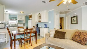 A spacious living area with a wooden dining table, chairs, a beige sofa, and a ceiling fan. - Walk to Shops & Dining: Houston Heights Home! (Houston)