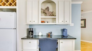A kitchen with white cabinetry, a marble countertop, a coffee maker, and a decorative horse sculpture. - Walk to Shops & Dining: Houston Heights Home! (Houston)