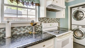 A kitchen with a stove, oven, and washing machine. - Walk to Shops & Dining: Houston Heights Home! (Houston)