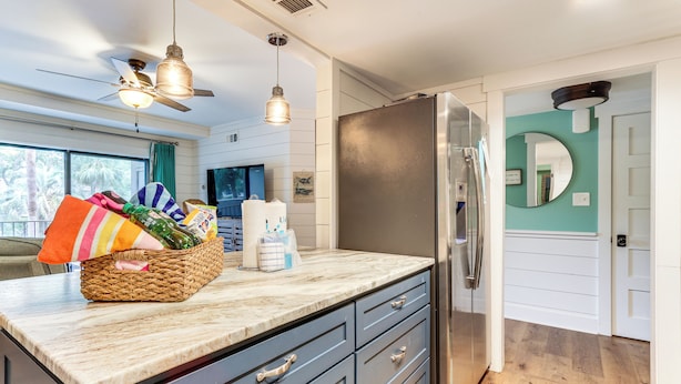 Una cocina moderna con una isla grande, refrigerador de acero inoxidable y una cesta de provisiones.