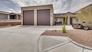 Un immeuble résidentiel doté de deux portes de garage, d’un patio agrémenté d’un cactus, ainsi que d’une petite table et de quelques chaises.