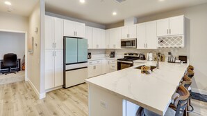 Une cuisine moderne avec des meubles blancs, un grand îlot central et un coin bar.