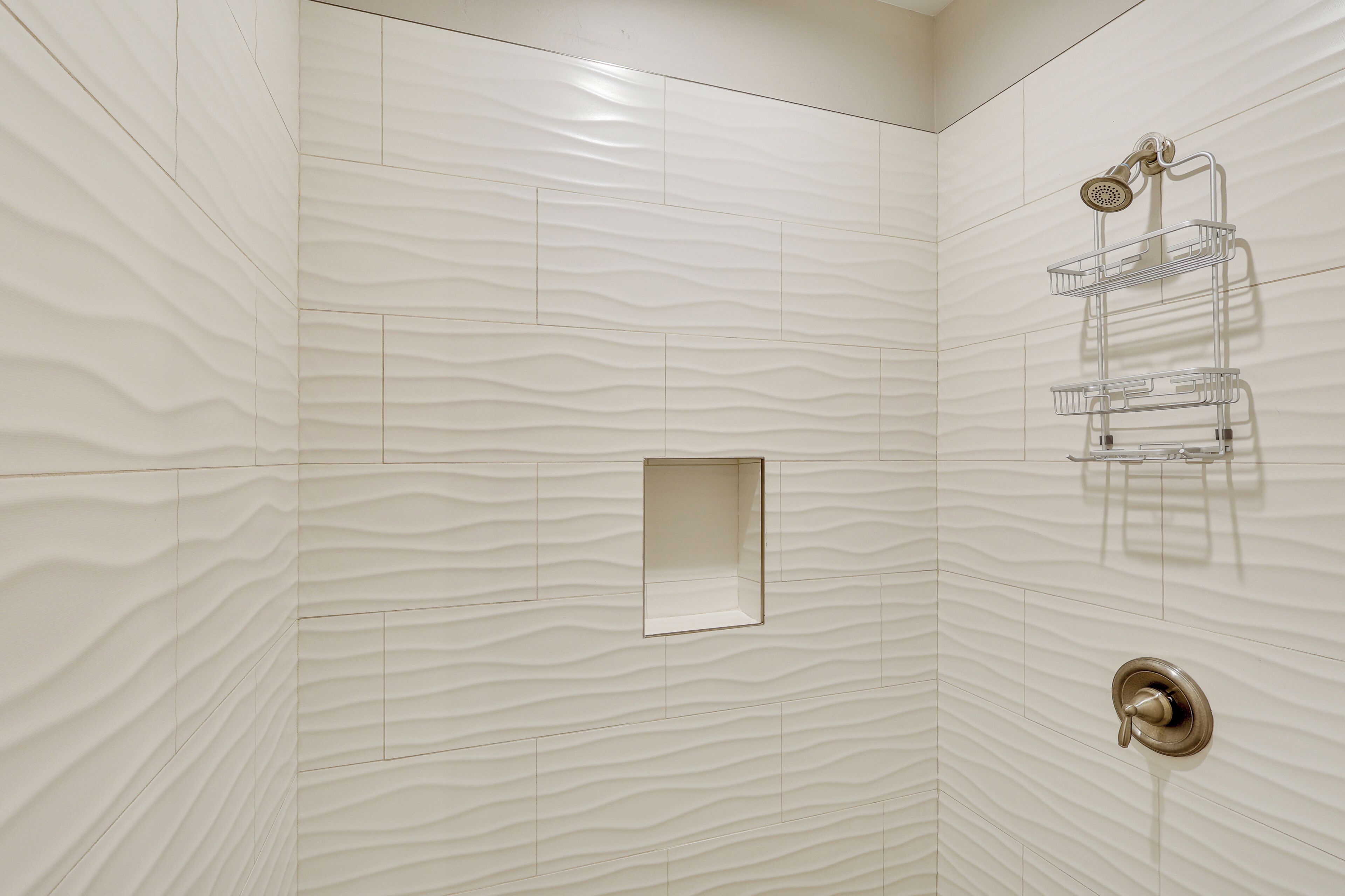 A bathroom with a textured wall, a shower area, and a towel rack.
