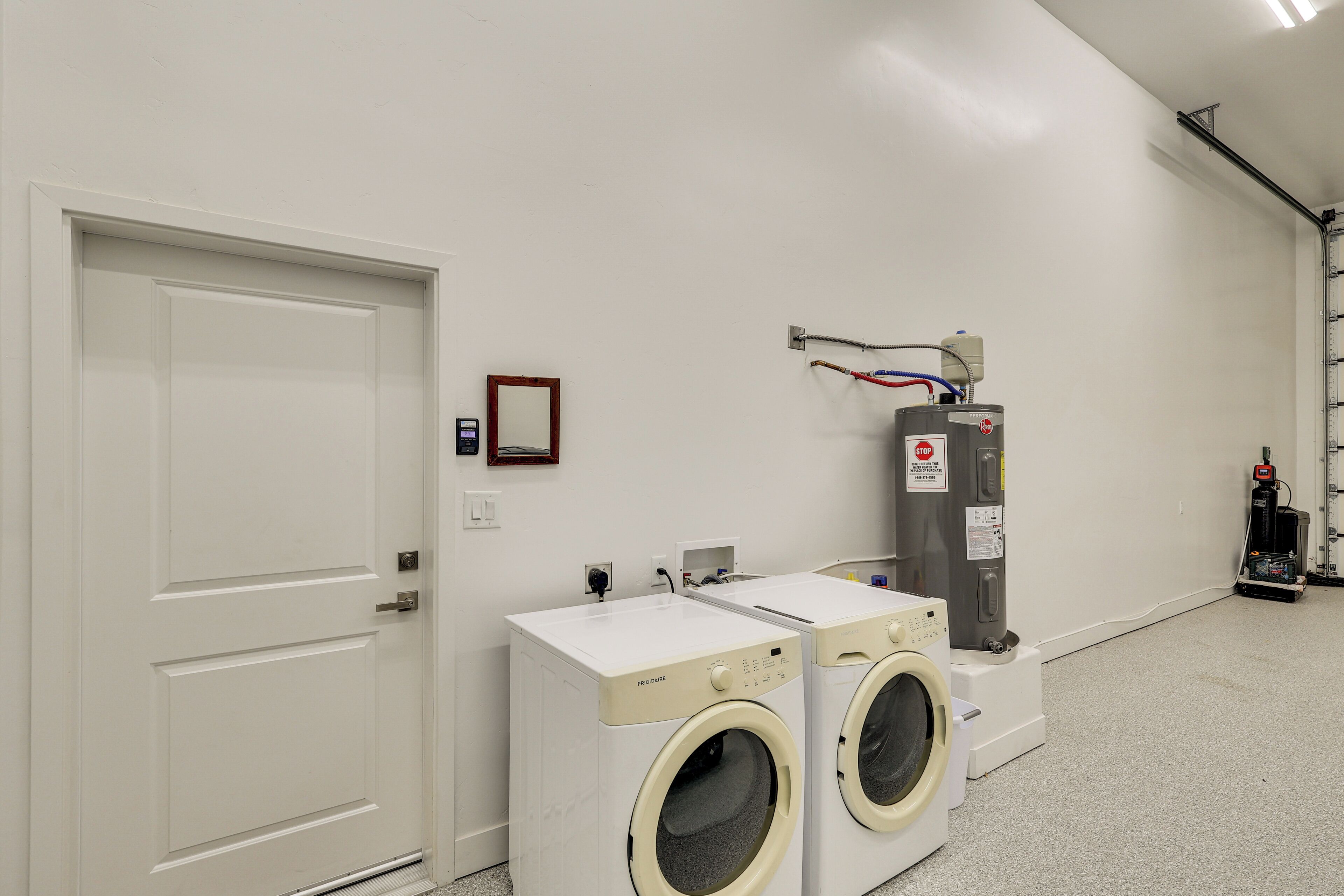 A laundry room with two front-loading washers, a water heater, and a control panel.