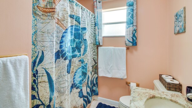 A bathroom with a shower curtain featuring a map design, a toilet, a sink, and a window. - < 1 Mi to Pennekamp: Tranquil Escape w/ Dock (Key Largo)