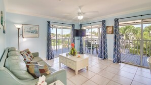 A living room with a sofa, coffee table, and a TV. There is a balcony with a view of the outside. - < 1 Mi to Pennekamp: Tranquil Escape w/ Dock (Key Largo)
