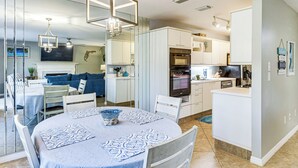 A modern kitchen with white cabinets, a built-in oven, and a dining area with a round table and chairs. - Steps to Ocean, Pool Access! Daytona Beach Gem (Daytona Beach Shores)