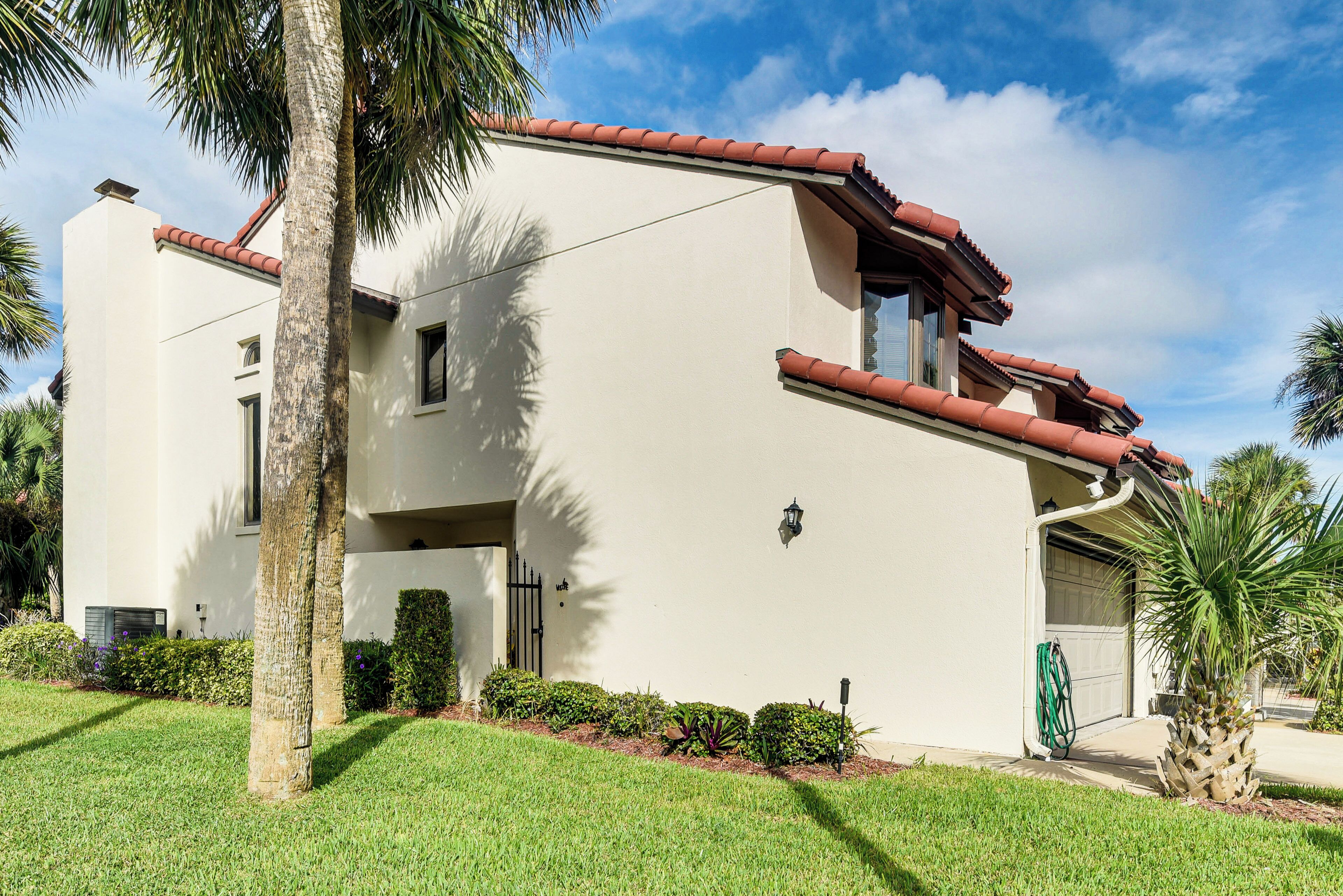 A two-story house with a red-tiled roof, a garage, and a well-maintained lawn.