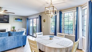 A dining area with a round table, chairs, and a chandelier. - Steps to Ocean, Pool Access! Daytona Beach Gem (Daytona Beach Shores)