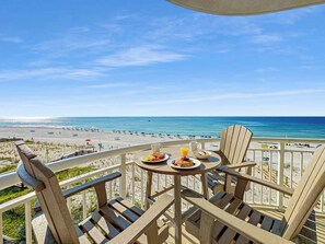 Balcón con mesa lista para el desayuno y vista a una playa.
