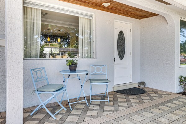 A patio area with two blue folding chairs, a small round table, and a potted plant. - Fish, Swim & Relax Poolside! Deerfield Beach Oasis (Deerfield Beach)