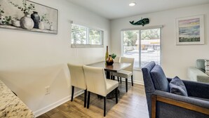 Un coin repas avec une table et des chaises, un tableau accroché au mur et une vue par la fenêtre.