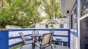 Une terrasse extérieure couverte, dotée d’une table et de chaises, et entourée d’une rambarde bleue.