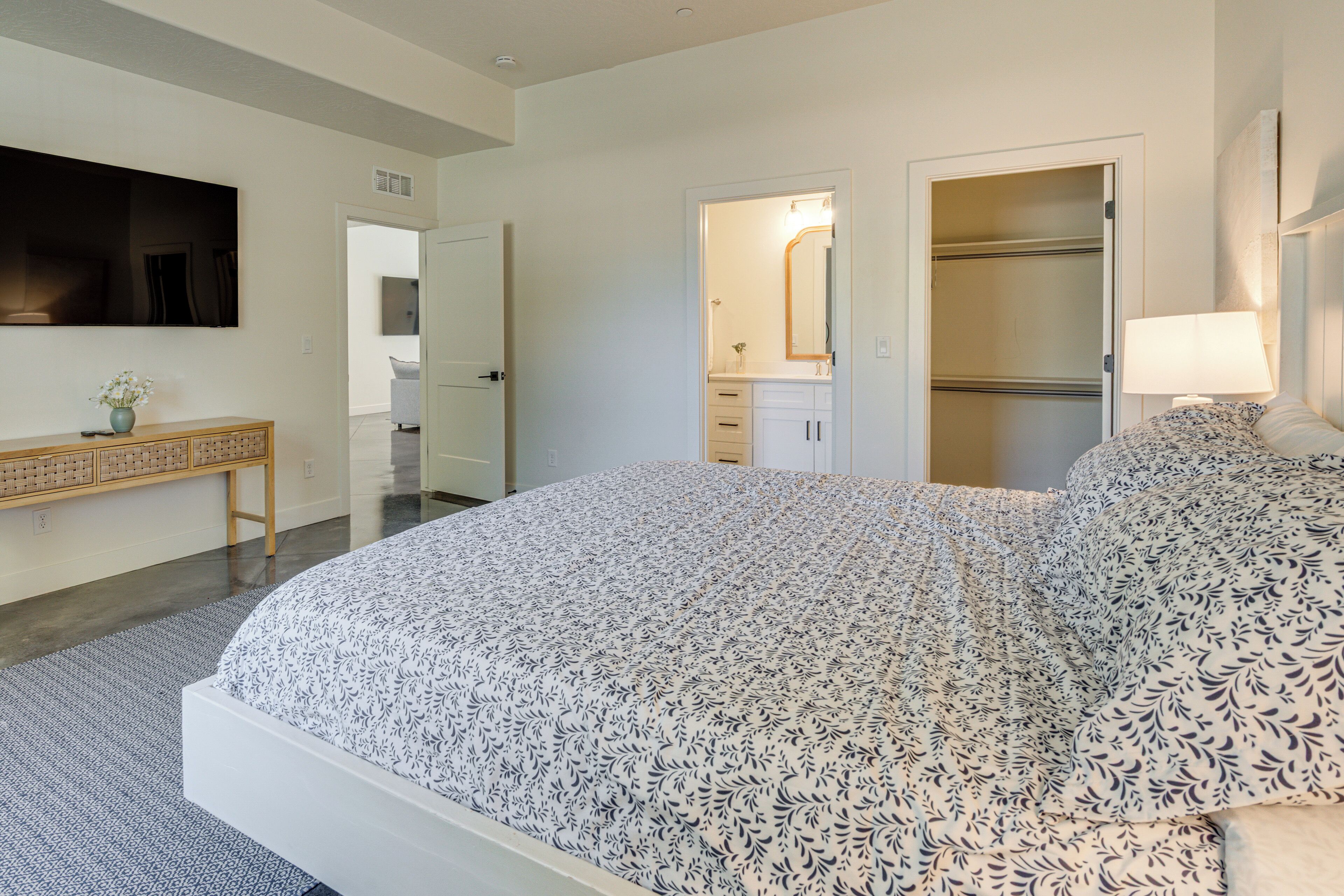 A bedroom with a large bed, a dresser, a mirror, and a walk-in closet.