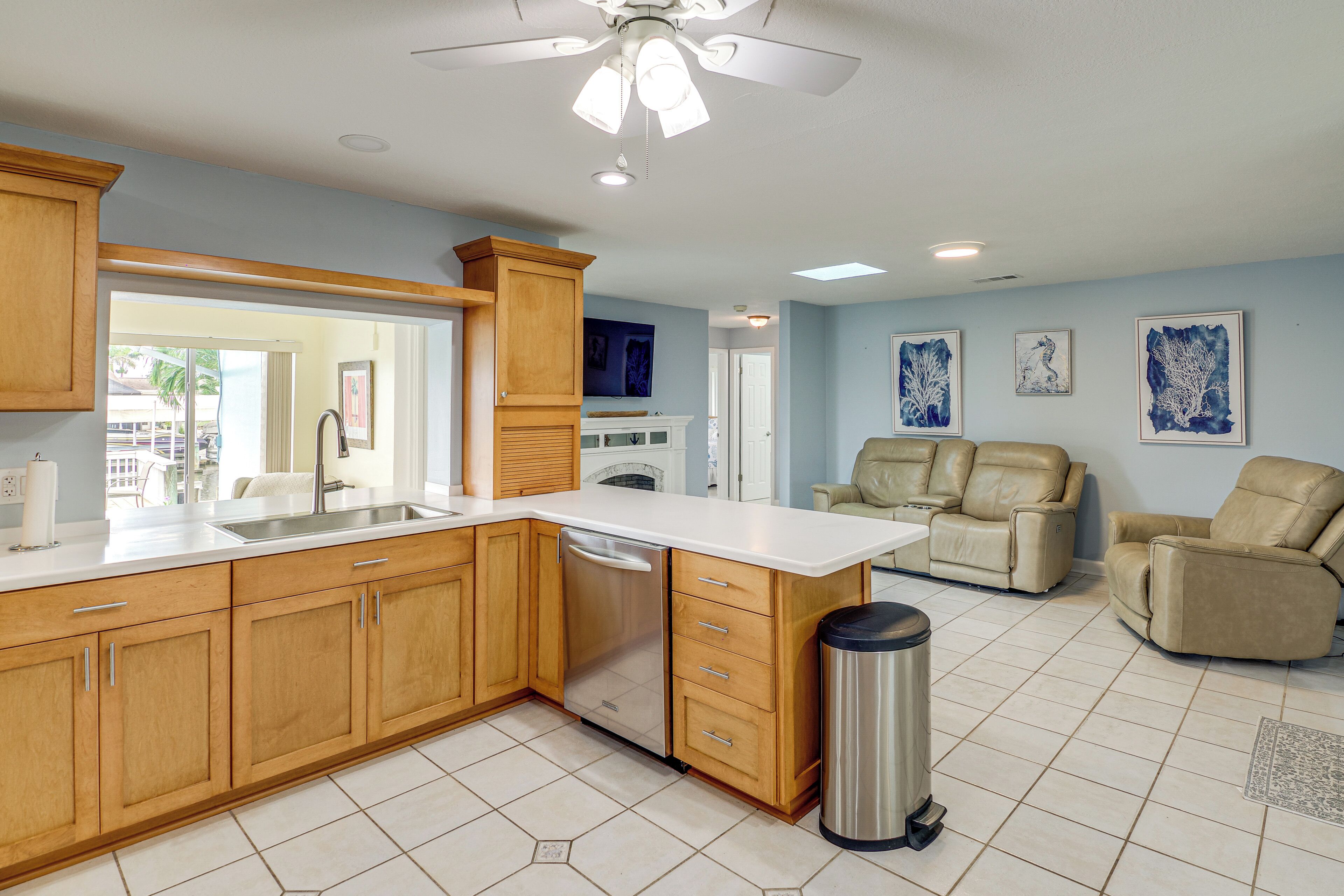 A kitchen with wooden cabinets, a dishwasher, and a ceiling fan.