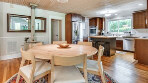 A modern kitchen with wooden cabinets, a central island, and a dining area with a round table and chairs. - Mtn Views, Deck, Porches & Patio: Asheville Escape (Asheville)