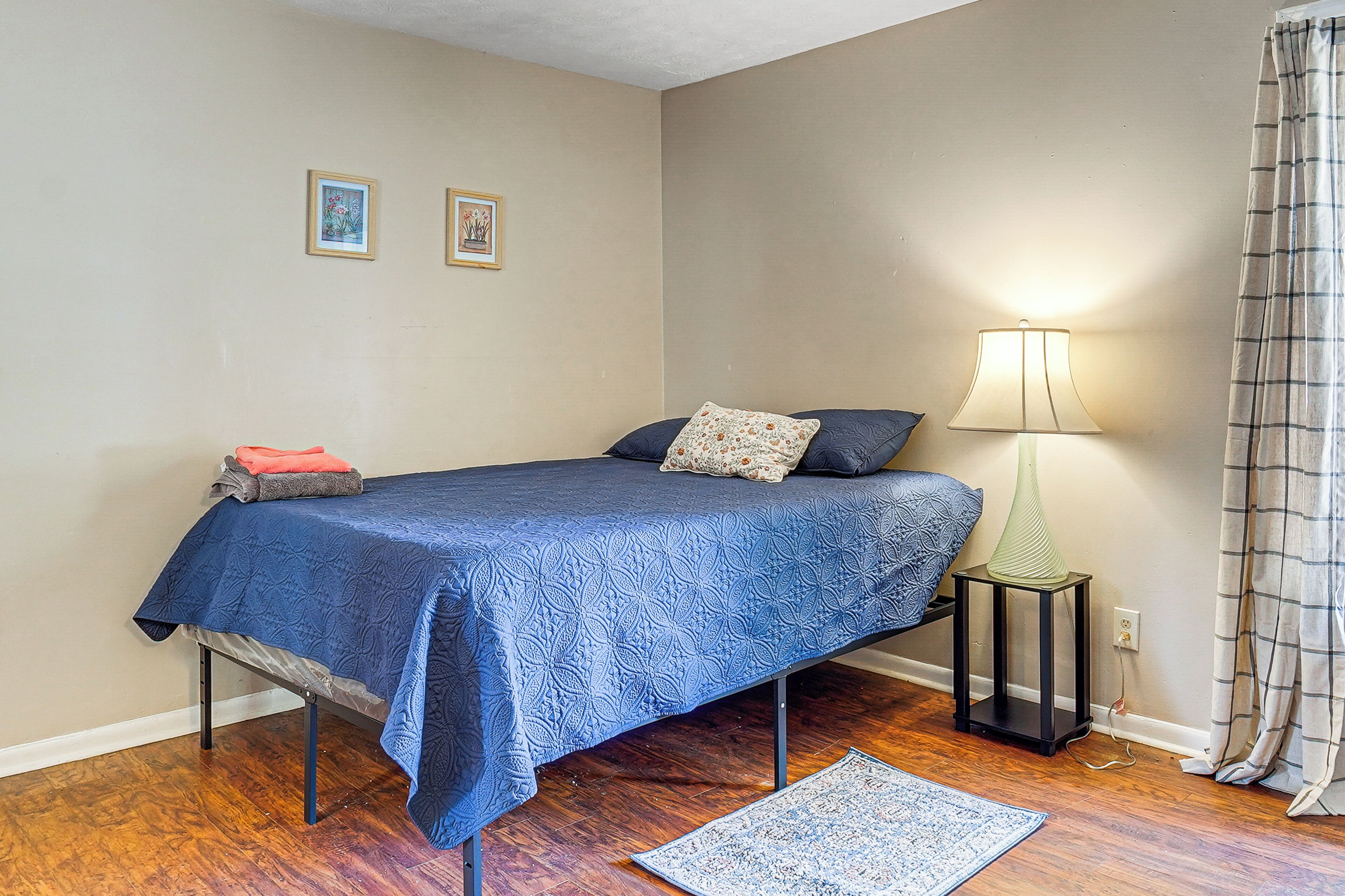 A bedroom with a bed, a nightstand, a lamp, and a rug.