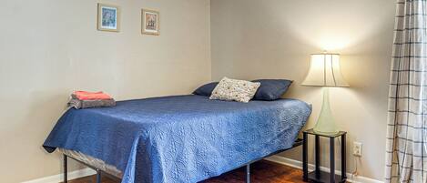 A bedroom with a bed, a nightstand, a lamp, and a rug.