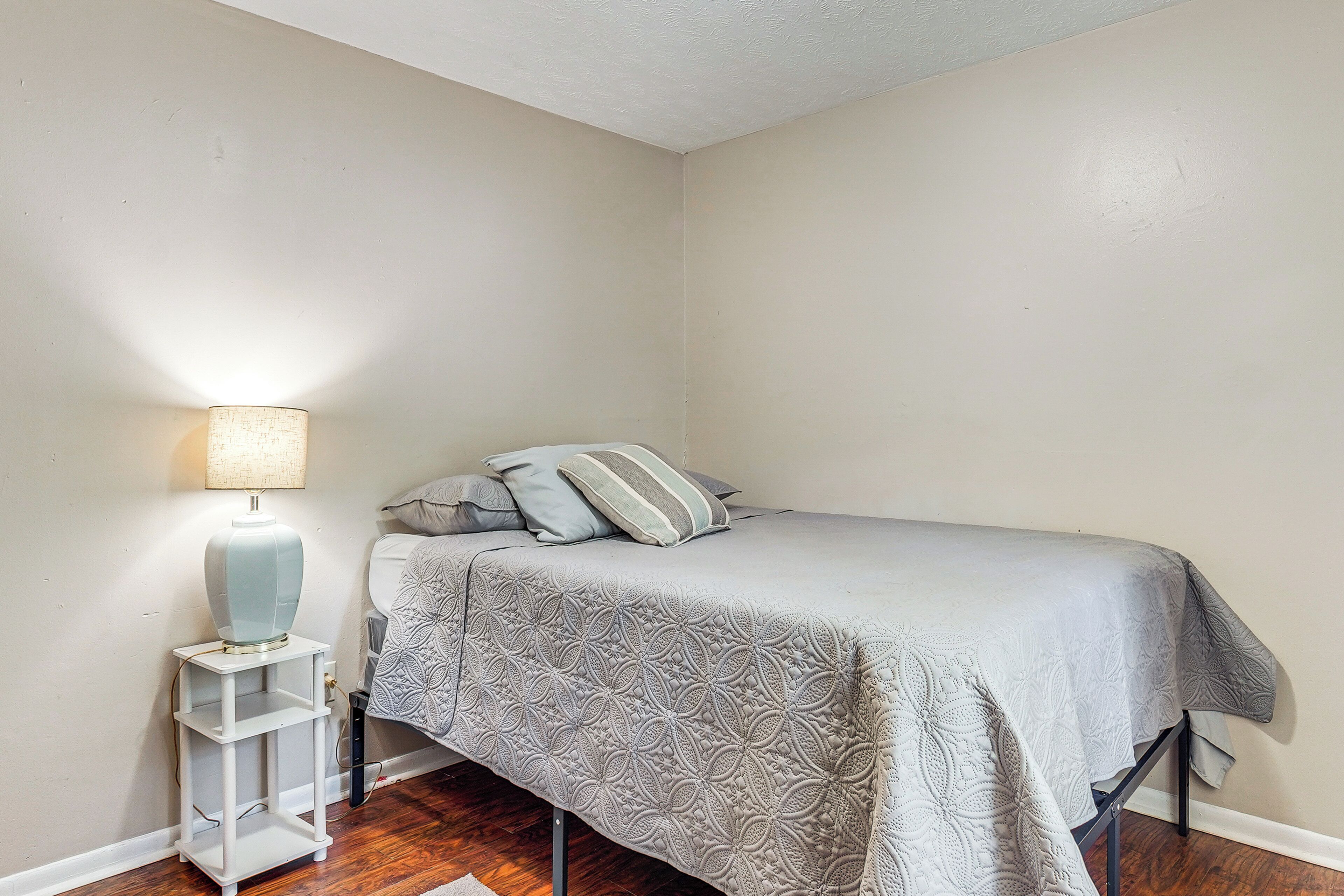 A small, neatly arranged bedroom with a bed, a nightstand, and a lamp.