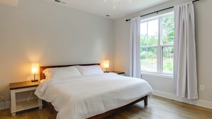 Une chambre à coucher avec un lit en bois, des tables de chevet et une fenêtre avec des rideaux.