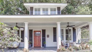 Une maison à deux étages avec un porche, une porte d’entrée en bois et un ventilateur de plafond.