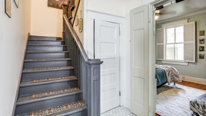 Un escalier orné de balustrades décoratives, une porte blanche et une chambre à coucher avec un lit et une fenêtre.