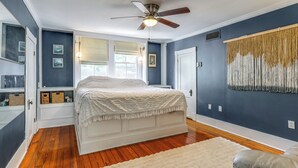 Une chambre à coucher avec un lit, un ventilateur de plafond, une fenêtre et une porte.