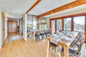 A spacious dining area with wooden tables and chairs, large windows offering views of the outdoors, and a stone accent wall. - Steps to Hiking: Sanctuary in Santa Ana Mtns (Murrieta)