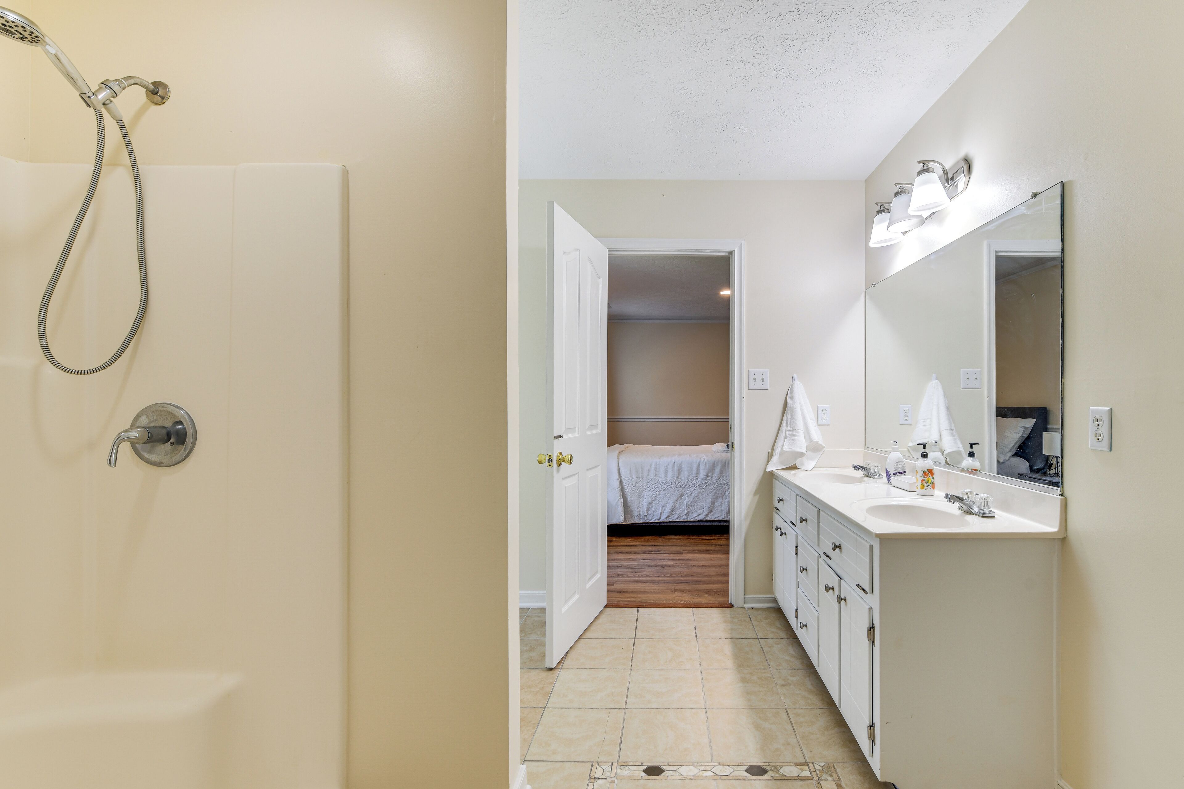 Un baño con ducha, lavamanos y espejo.