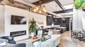 A modern living room with a fireplace, seating, and a kitchen in the background. - Modern Dtwn Condo w/ Balcony in Hendersonville (Hendersonville)