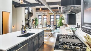 A modern kitchen with a central island, black cabinetry, and a stainless steel stove. - Modern Dtwn Condo w/ Balcony in Hendersonville (Hendersonville)
