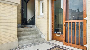 A building entrance with a set of concrete steps leading to a door with a wooden frame and glass panels. - Modern Dtwn Condo w/ Balcony in Hendersonville (Hendersonville)