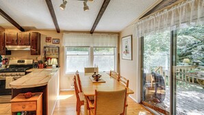 A kitchen with wooden cabinets, a built-in stove, and a dining area with a table and chairs. - Quiet All-season Creekside Escape in Upstate! (Berlin)