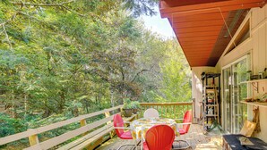 A wooden deck with a table and chairs, surrounded by trees. - Quiet All-season Creekside Escape in Upstate! (Berlin)