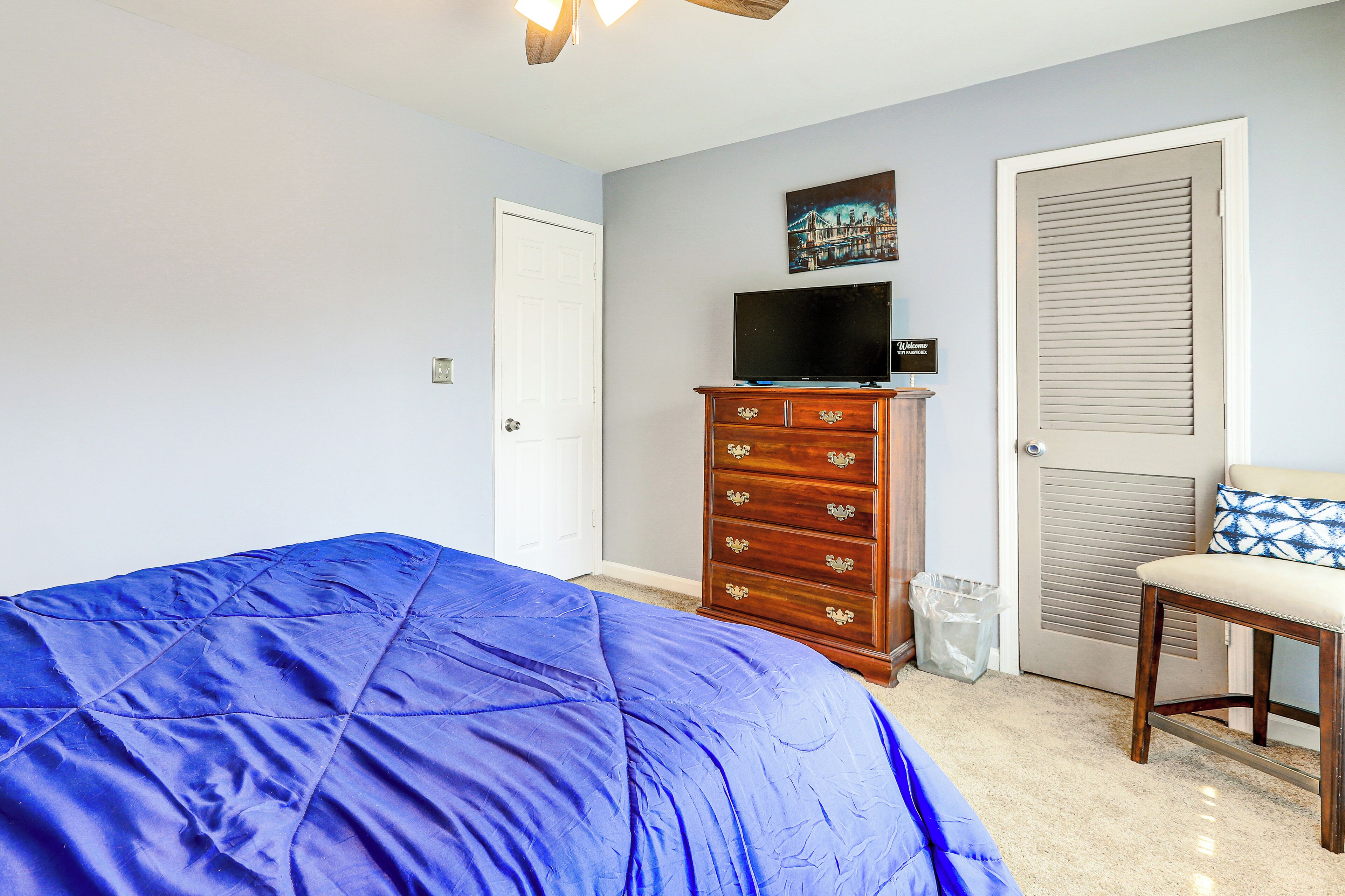 Une chambre à coucher avec un grand lit, une commode, un téléviseur et une porte avec une fenêtre.