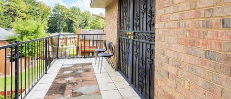 A balcony with a tiled floor, a metal railing, and a brick wall.